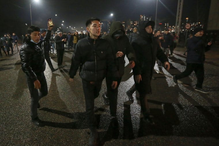 Manifestanti in Kazahstan noaptea in orasul Almaty.  Patru persoane au bratele legate in prim plan